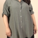 Une personne portant la Chemise en viscose, une chemise à boutons vert olive avec des manches roulées, associée à un pantalon noir. Mode Grande taille