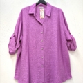 Une Chemise en viscose, ample et à manches longues, de couleur violette, est exposée sur un cintre noir contre un mur blanc. Mode Grande taille