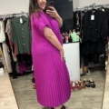 Femme souriante dans un magasin de vêtements prenant un selfie dans un miroir, portant la Robe longue plissée violine. Mode Grande taille
