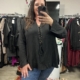 Femme prenant un selfie dans un magasin de vêtements, portant la Blouse à laçage noire et un jean bleu. Mode Grande taille