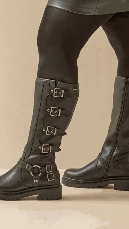 Le modèle porte des Bottes mollets larges 2XL Penelope - Gabylou, avec des collants noirs et une jupe noire, sur fond beige. Mode Grande taille