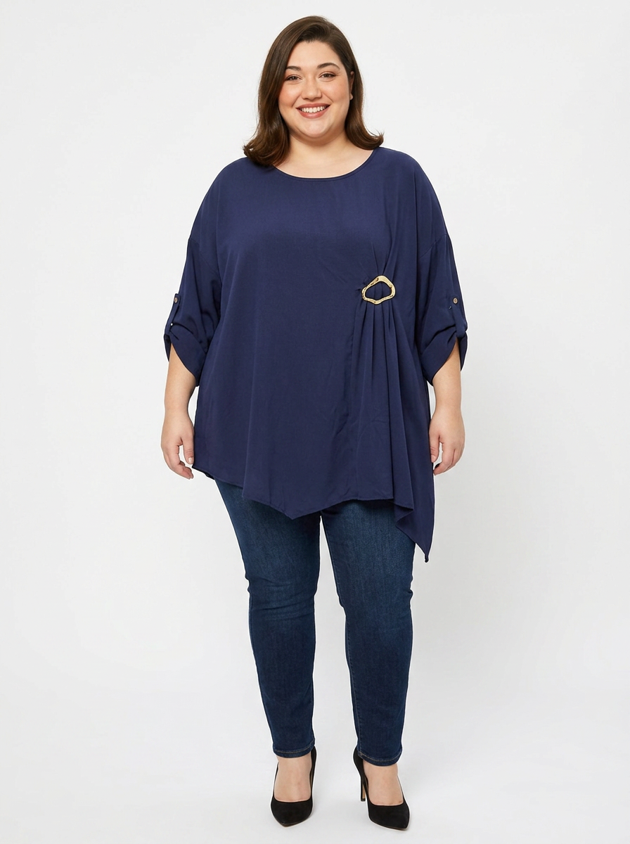 Blouse grande taille bleu marine col rond avec boucle dorée, portée par une femme ronde