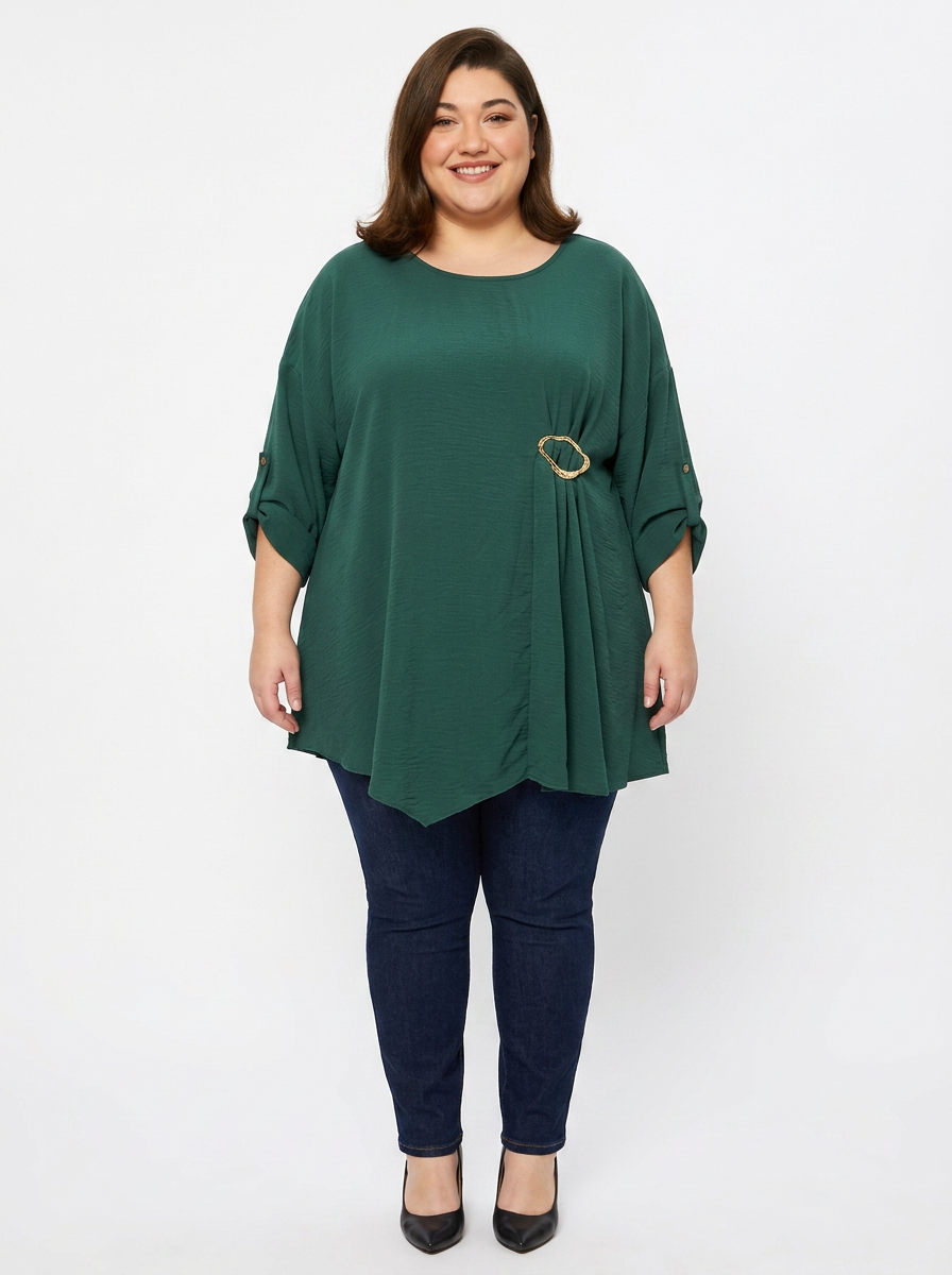 Blouse grande taille vert sapin col rond avec boucle dorée, portée par une femme ronde
