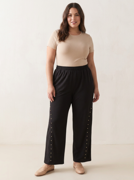 Pantalon large à clous dorés grande taille noir porté par une femme ronde