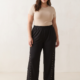 Pantalon large à clous dorés grande taille noir porté par une femme ronde