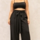 Pantalon taille haute grande taille noir fluide à ceinture nouée, porté par une femme ronde