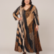 Robe longue grande taille imprimée lurex noir, beige et camel, col V et manches longues, portée par une mannequin ronde