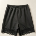 Short noir avec bande de dentelle florale au bas des jambes, vu à plat